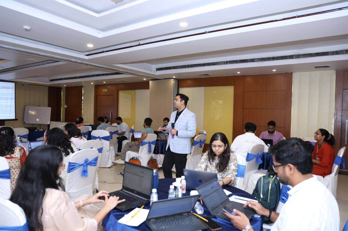 A past AI Edge workshop: participants at tables with laptops open while Saket walks the room